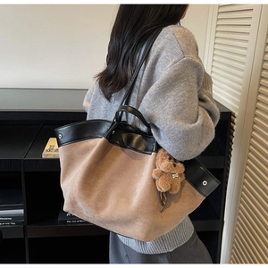 Detail of khaki suede tote bag with black leather trim and cute brown bear plush charm