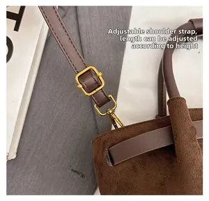 Detailed view of adjustable shoulder strap with gold hardware on brown suede handbag