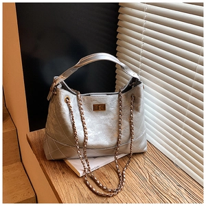 Detail of silver quilted tote bag with metallic finish, chain strap and gold twist lock