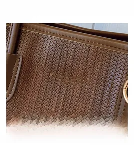 Close-up of dark brown woven leather texture with gold stamped fashion lettering