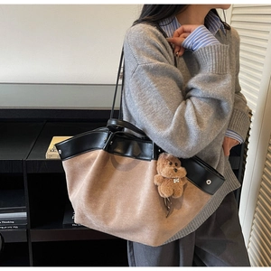 Detail of color-block tote bag with suede texture and brown teddy bear charm