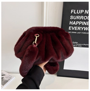 Detail of burgundy faux fur pleated cloud clutch bag with gold metallic clasp and tassel