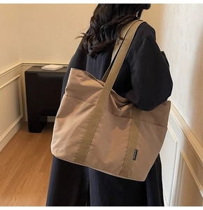 Detail of khaki nylon tote bag with wide strap and side woven label for students