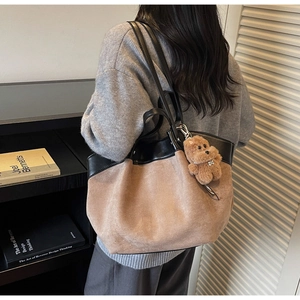 Detail view of khaki suede tote bag with black leather handles and bear charm