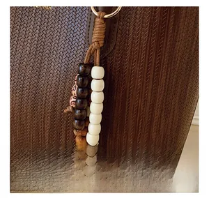 Detail of dark brown woven leather texture with decorative wooden beads and gold ring