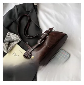 Detail view of vintage dark brown tote bag with metal key charm and leather straps