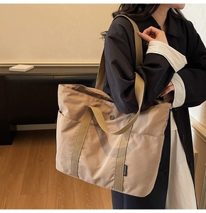 Close-up of khaki tote bag with dual straps and side pocket in a home setting