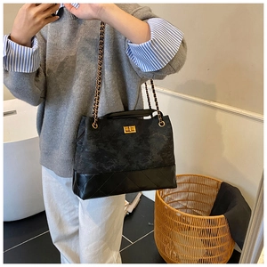 Detail of black quilted chain bag with gold twist lock on a shoulder strap model