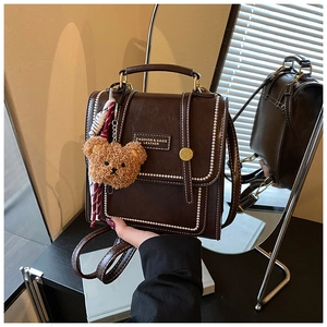 Detail of dark brown vintage backpack with bear charm and silk scarf decoration