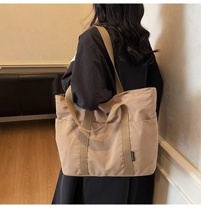 Detail of khaki tote bag showing wide fabric straps and durable canvas texture on shoulder