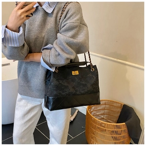 Detail of black quilted shoulder bag with chain strap and vintage metal twist lock