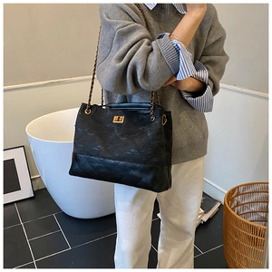 Detail showing the quilted leather base and textured fabric of the chain crossbody bag