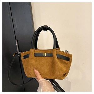 Detail of brown suede tote with black leather straps and gold N-shaped buckle
