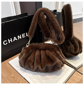 Detailed view of brown faux fur pleated cloud bag with textured handle on a wooden surface