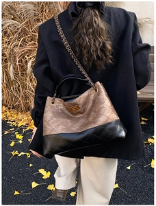 Close-up of quilted black leather chain bag with gold hardware in autumn scenery