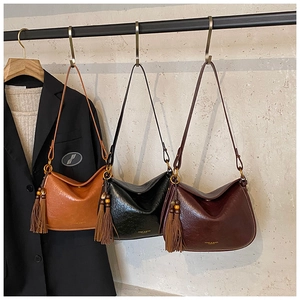 Three retro faux leather shoulder bags in brown, black, and burgundy with tassel detail