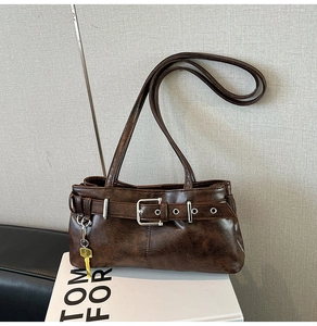 Close-up of vintage brown leather tote featuring a bold metal buckle and key charm