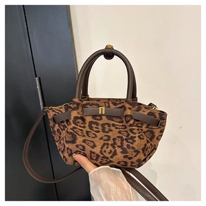 Detailed close-up of leopard print handbag with premium brown leather straps and gold hardware