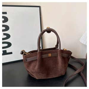 Detail of deep brown frosted suede handbag with elegant golden metal hardware and smooth handle