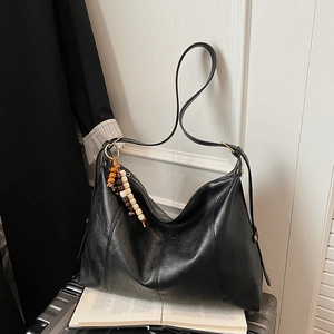 Macro shot of large black tote bag with glossy finish and colorful beaded tassel detail