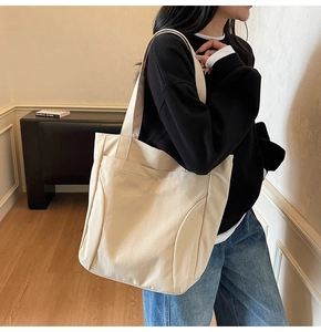 Detail of embroidered lettering on beige canvas tote bag with spacious interior view