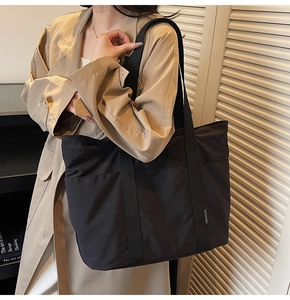 Detailed shoulder view of a large black minimalist tote bag with durable woven handles
