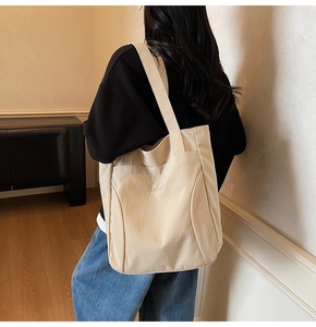 Detailed close-up of a large beige canvas tote bag with embroidered logo and stitching