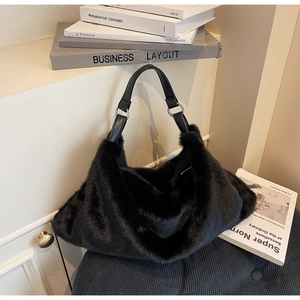 Détail d'un sac hobo en fausse fourrure noire avec bandoulière en cuir et boucles argentées