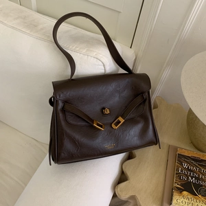 Close-up of dark brown leather tote bag with gold buckle and embossed brand logo detail