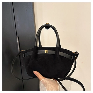 Close-up of black frosted suede handbag with gold geometric metal and leather handle