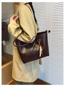 Detail of vintage brown tote bag featuring woven texture and decorative beaded tassel