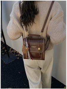 Detail of vintage brown leather backpack with bear charm and woven strap on model