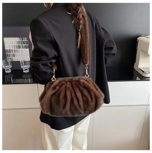 Rear view of model wearing a brown faux fur cloud bag with gold metal buckle accents