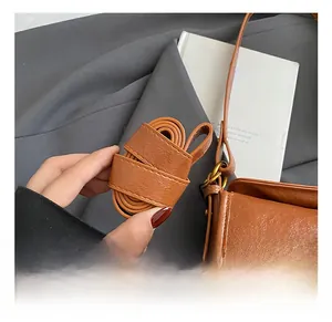 Detail of adjustable brown leather strap with lychee texture and gold-tone hardware on bag