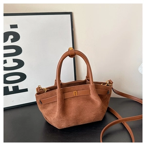 Close-up of brown frosted suede handbag showing leather handle and gold buckle detail