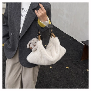 Dettaglio della borsa a tracolla in peluche bianca con manici in pelle e ciondolo a coniglio