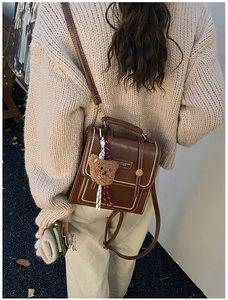 Detail of vintage brown leather backpack with contrast stitching and teddy bear charm