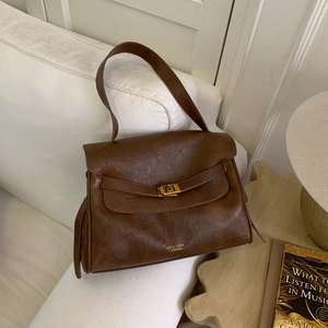 Close-up of brown leather tote bag showing vintage texture and gold metal clasp detail
