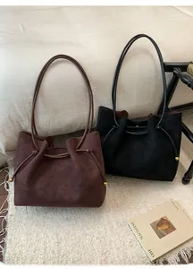 Detail of dark brown and black suede tote bags with drawstring and gold metal bead accents