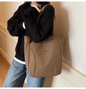 Detailed view of brown canvas tote bag with Midolai embroidery and wide shoulder strap