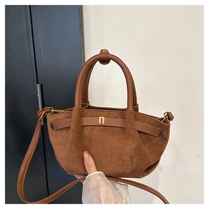 Detail view of brown matte suede texture and leather handle on a vintage handbag