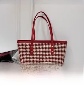 Detailed view of red and white woven plaid tote bag with slim leather handles and gold studs
