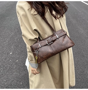 Detail of vintage brown leather bag with buckle strap and key pendant decoration