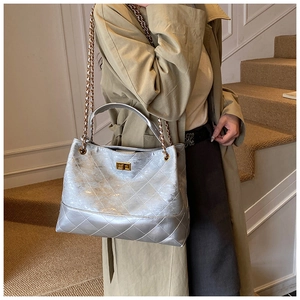 Detail of silver quilted handbag with golden twist lock and metal chain strap