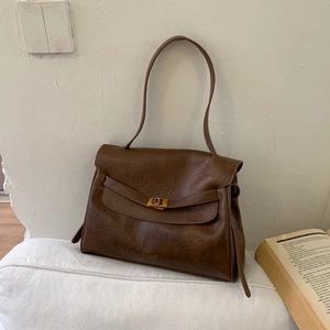 Detail of vintage brown tote bag with gold swivel lock and elegant brand logo