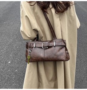 Close-up of vintage dark brown leather shoulder bag with buckle and gold key charm