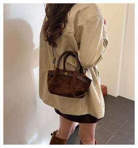 Detail view of the vintage brown matte handbag with round handles and metal buckle accents