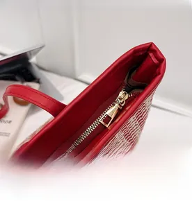 Detail shot of smooth gold-tone zipper and red woven leather tote bag with white texture