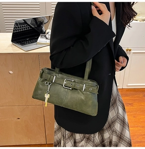 Detail of vintage dark green shoulder bag with leather strap buckle and gold key pendant
