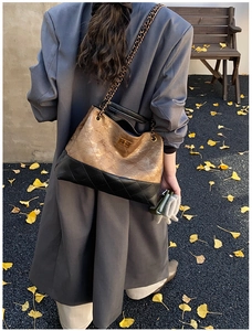 Detail of quilted two-tone shoulder bag with gold chain strap in a classic autumn setting